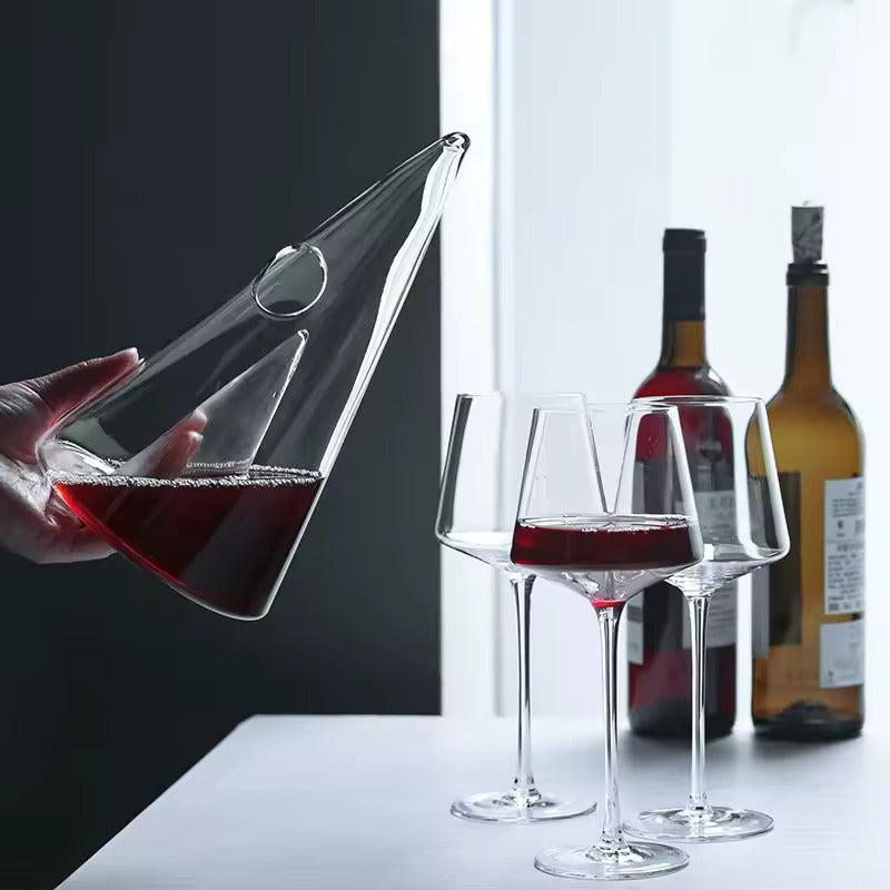 Transparent CrystalPyramid™ wine decanter being poured with red wine into glasses, showcasing elegant glassware design.