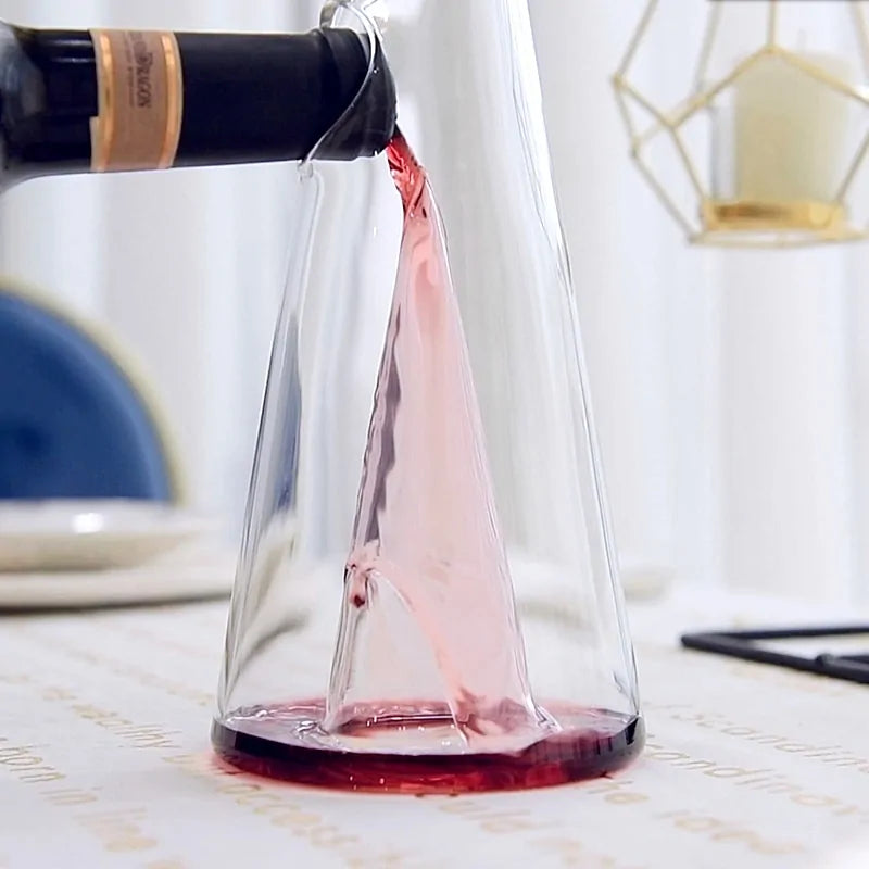 Transparent CrystalPyramid™ wine decanter showcasing elegant wine pouring from a bottle in a refined setting.