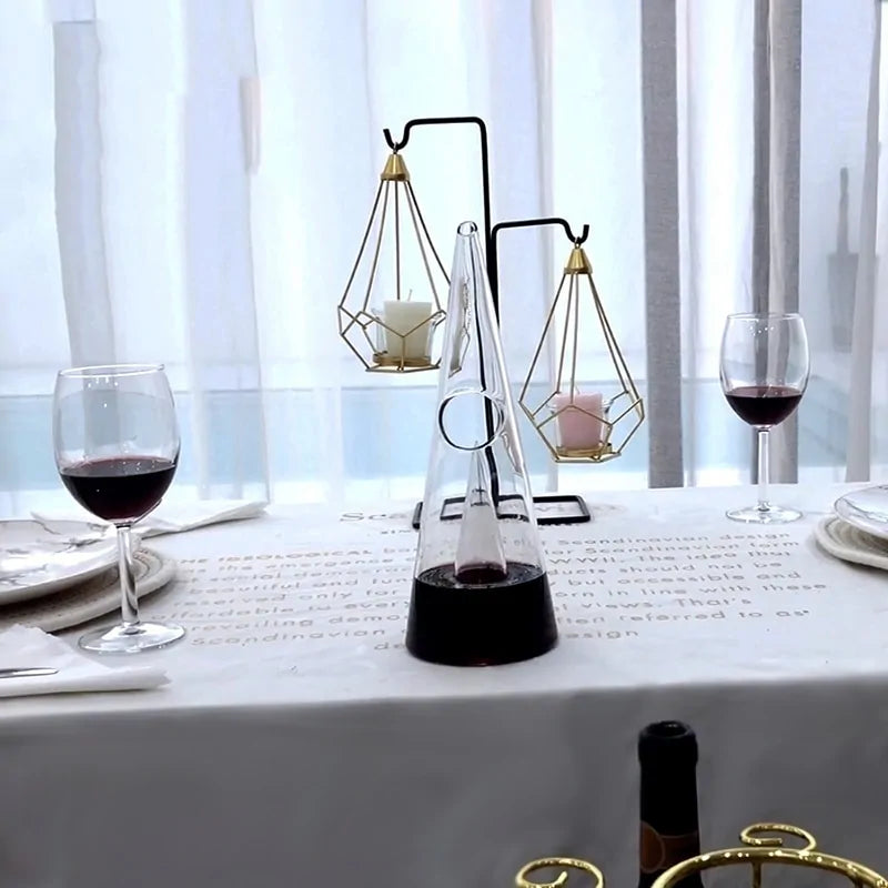 Transparent CrystalPyramid™ wine decanter on elegant dining table with wine glasses.